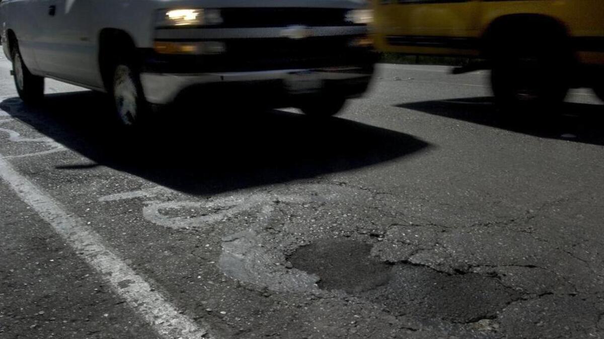 Vehicles drive through potholes and cracks in the street along Auburn Blvd. between Watt Ave. and Orange Grove St. in Sacramento on May 26, 2005.