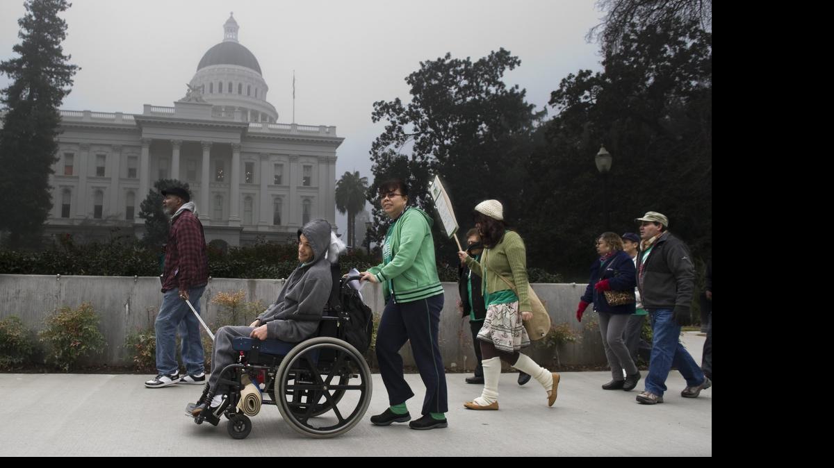 
Ramon Gaytan is pushed by his mother Manuela Gaytan as they joined a 2011 march at the Capitol over proposed cuts to in-home supportive services.
