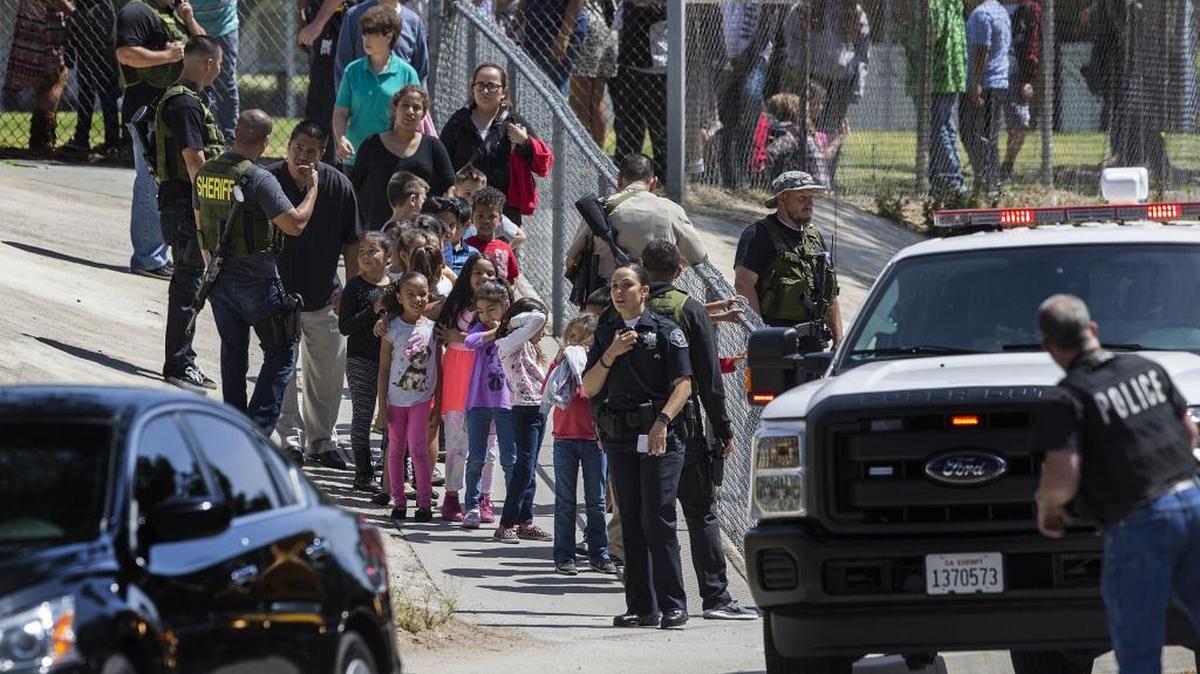 San Bernardino police officers help evacuate children to waiting school buses after a shooting inside North Park Elementary School on April 10, 2017 in San Bernardino. A new state audit faults local and state school officials for lax oversight of school safety plans.
