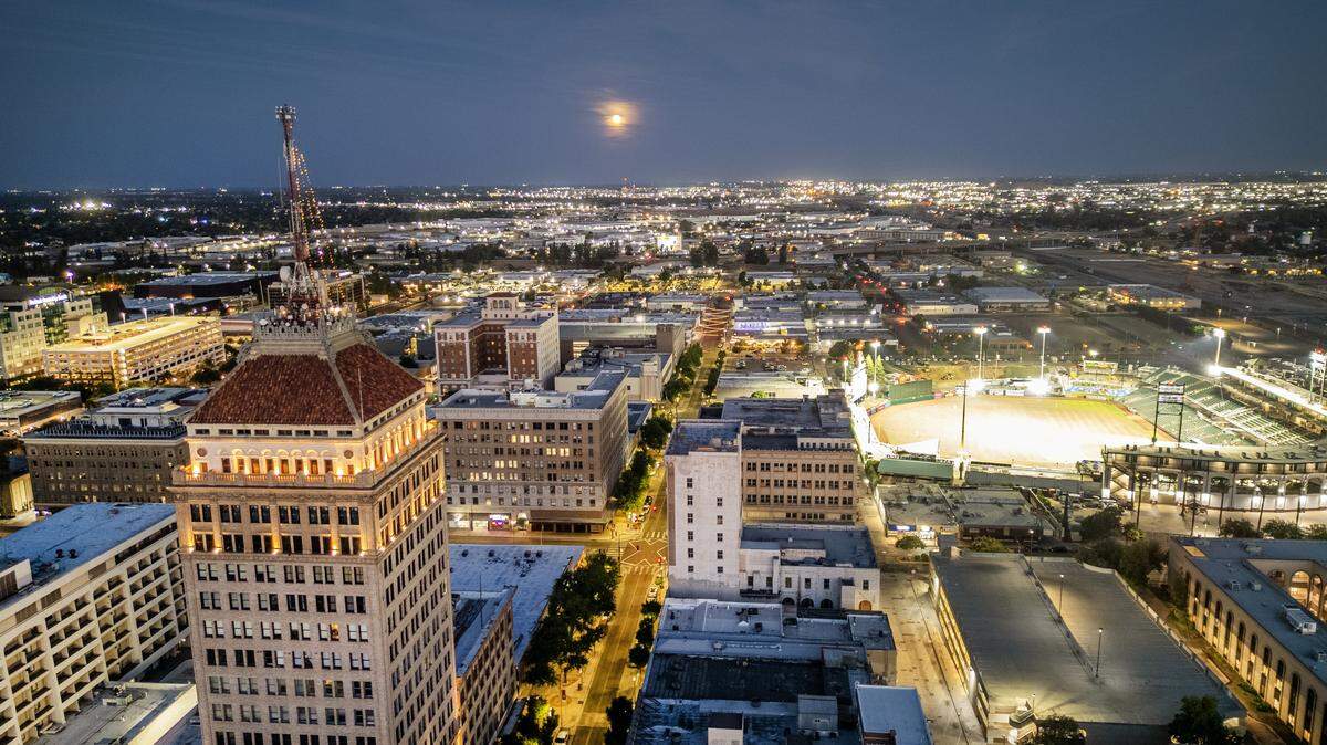 The moon rises above the downtown Fresno skyline viewed from a drone camera on Tuesday, June 10. 2025. Fresno is one of many California cities that hires private lobbying firms to represent it in Sacramento. 