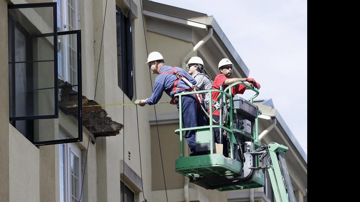 
A worker measures the remaining wood of an apartment building balcony that collapsed, killing six college students and injuring several others, in Berkeley in June.
