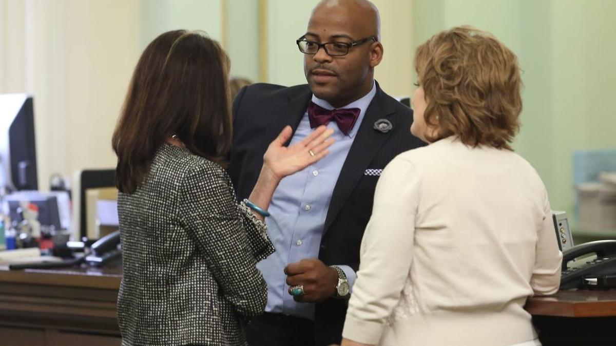Assemblyman Isadore Hall, D-Compton, talks with Republican Assembly members Diane Harkey of Dana Point, left, and Shannon Grove of Bakersfield, right, after the Assembly approved his bill banning smoking in home day care centers on April 21, 2014.