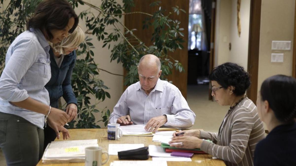 
Gov. Jerry Brown, center, takes action Friday at his Capitol office on some of the hundreds of bills awaiting his signature.
