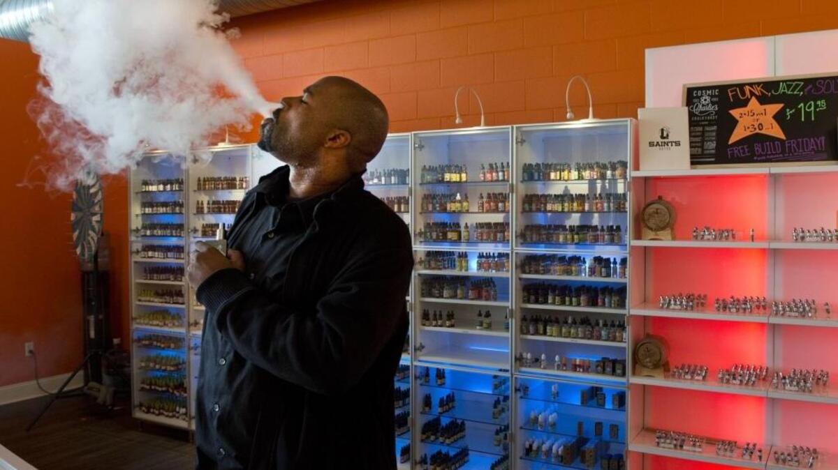 A sales associate at The Vapor Spot on J Street in midtown Sacramento exhales smoke from his e-cigarette on Wednesday, Jan. 27, 2015.