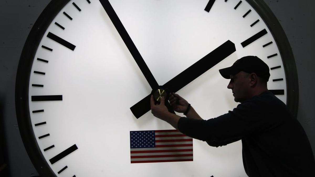 A worker in Medfield, Mass., adjusts a clock on March 7, 2014.