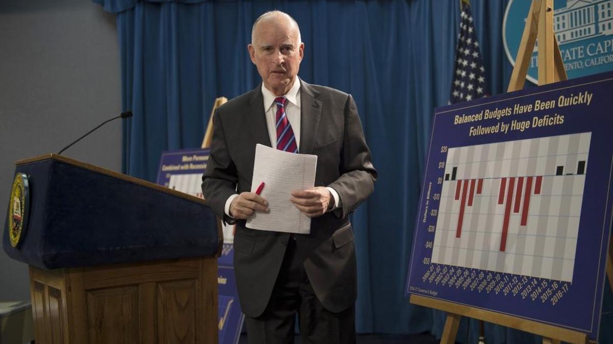 Gov. Jerry Brown carries notebook paper outlining his proposed 2016-17 state budget after a Capitol news conference on Jan. 7. The budget acknowledges a growing cost for state retiree health care but doesn’t propose any more spending to whittle down an $80.3 billion unfunded liability identified in a new report.