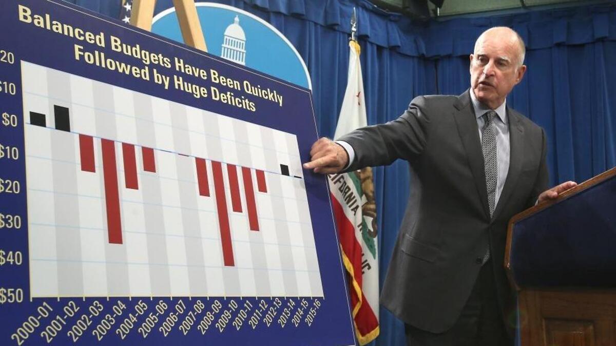 Gov. Jerry Brown points to a chart showing how balanced budgets are quickly followed by large budget deficits as he discusses his revised state budget plan at the Capitol on May 14, 2015.