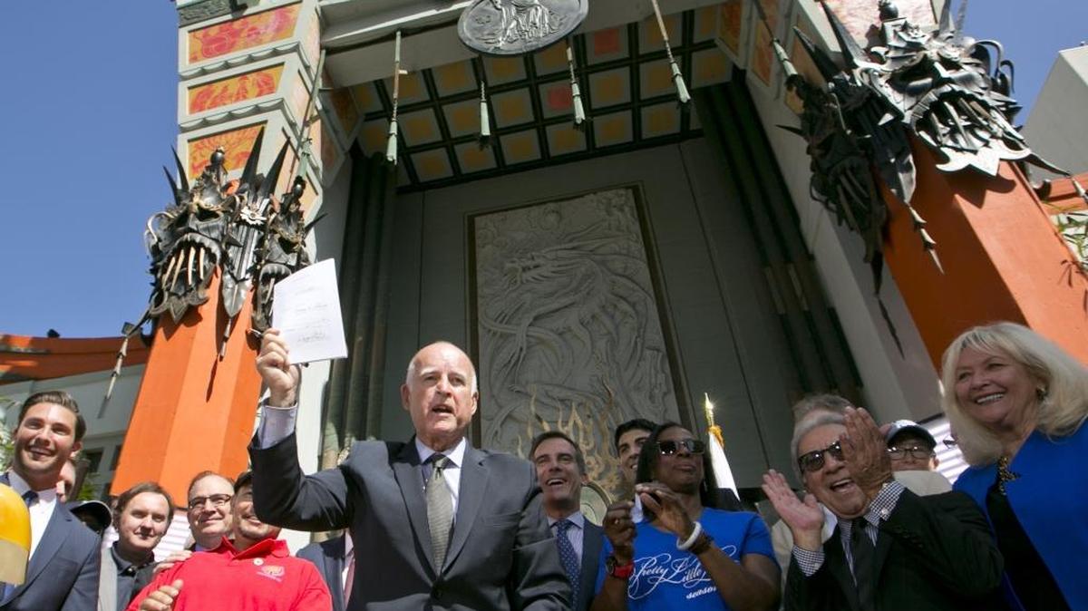 
California Gov. Jerry Brown holds up AB 1839, The Expanded Film and Television Job Creation Act, after signing the legislation into law, in front of TCL Chinese Theatre in Los Angeles, on Sept. 18, 2014. The extension and expansion of the program already has attracted four TV shows, the state film office says.
