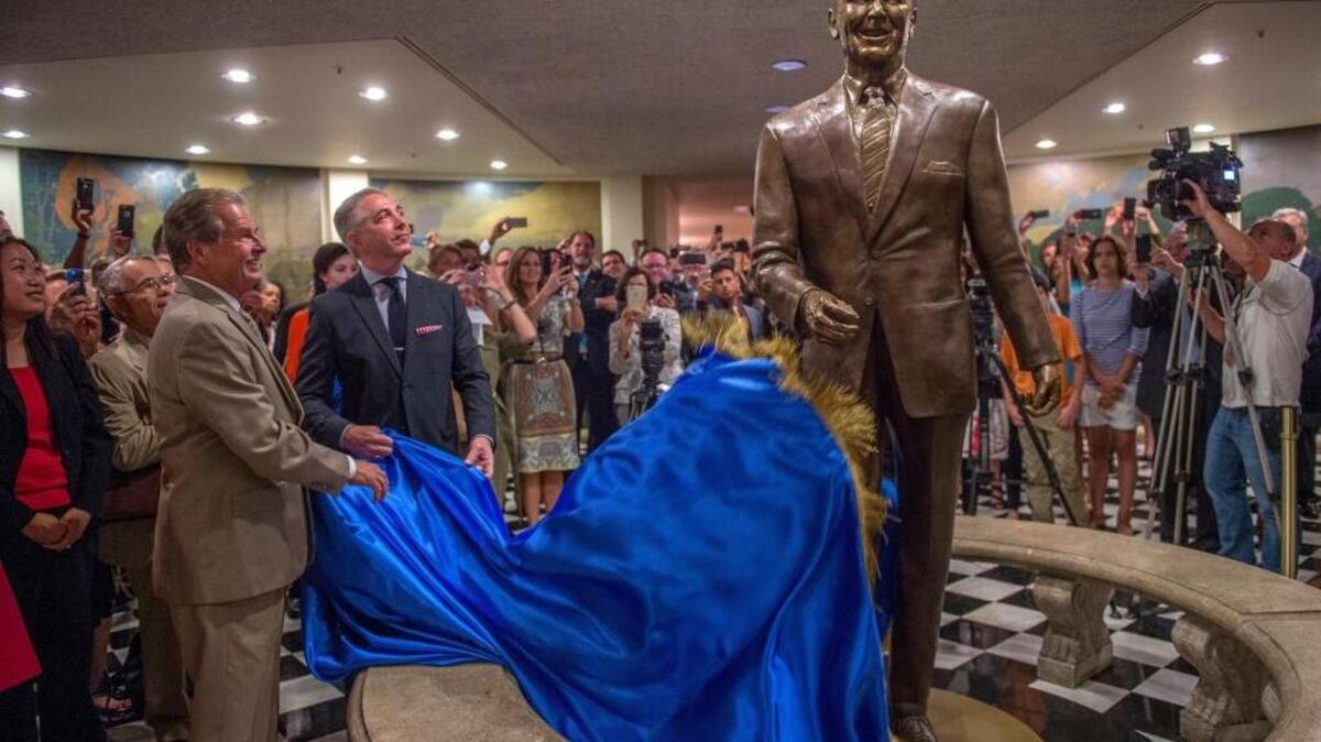 Sculptor Douglas Van Howd, left, and Douglas Elmets, chairman of the Ronald Reagan Centennial Capitol Foundation, second from left, unveil the 8-foot-tall bronze statue of the former California governor and president in the Capitol basement on June 22, 2015.