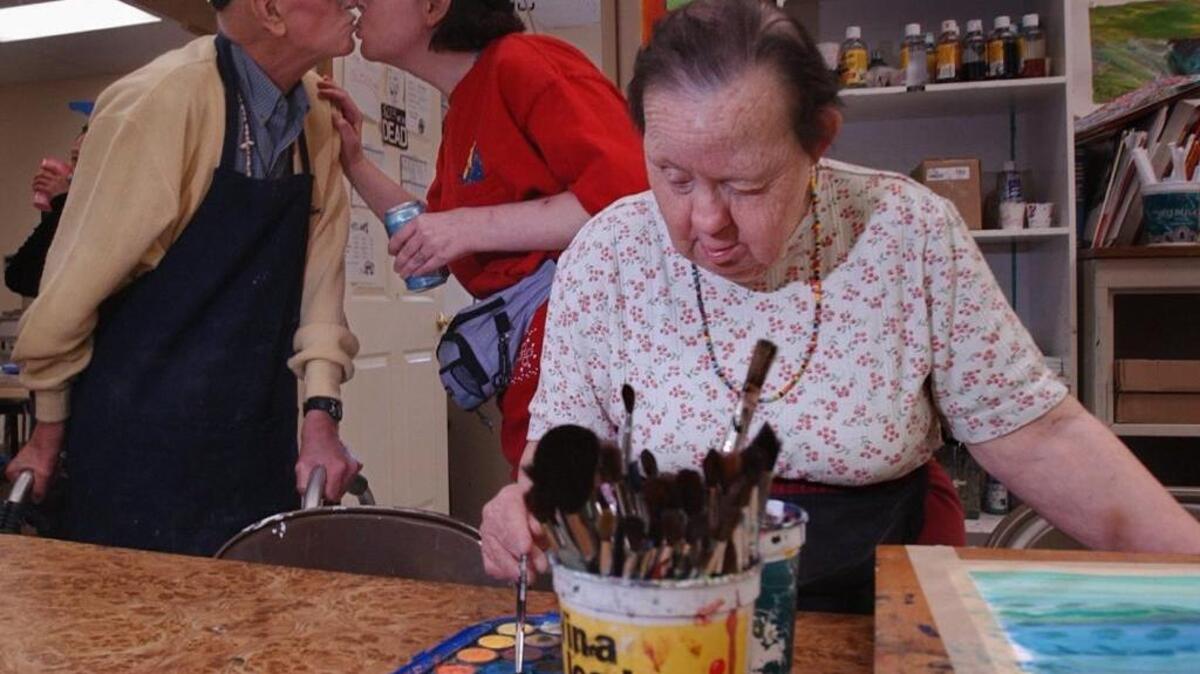 Irene Pinole practices her art at the Short Center, a nonprofit fine arts program for the disabled, in May 2004. While Irene paints a watercolor reminiscent of the ocean, her group home roommate, Terry Gordon, and classmate, Joe Conti, kiss.