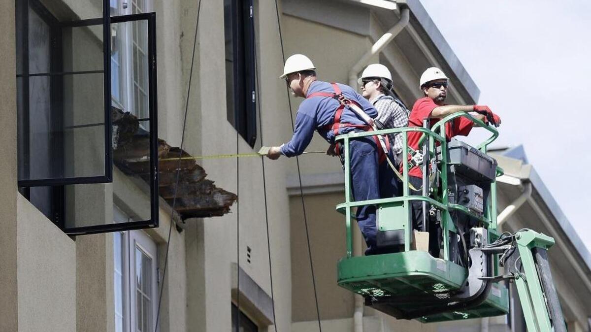 A worker measures near the remaining wood of the Berkeley apartment building balcony that collapsed, killing six college students and injuring several others, in June.