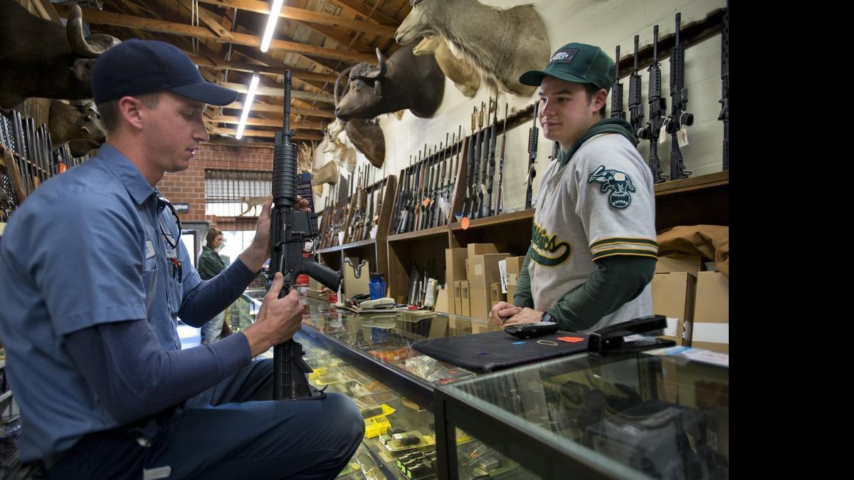 
Matt Dittmer, 26, left, holds a semi-automatic rifle he is purchasing with salesperson Blake Prior at Auburn Outdoor Sports on Dec. 11, 2013 in Auburn. Californians are buying nearly a million firearms a year, but the state’s rate of gun owmership is well below the national average, according to a new study.
