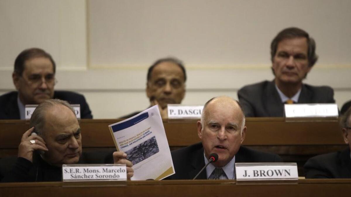 California Gov. Jerry Brown, front, right, flanked by Minsignor Marcelo Sorondo, shows a paper during a workshop organized by Vatican on the climate change, at the Casina Pio IV, at the Vatican, Saturday Nov.4, 2017.