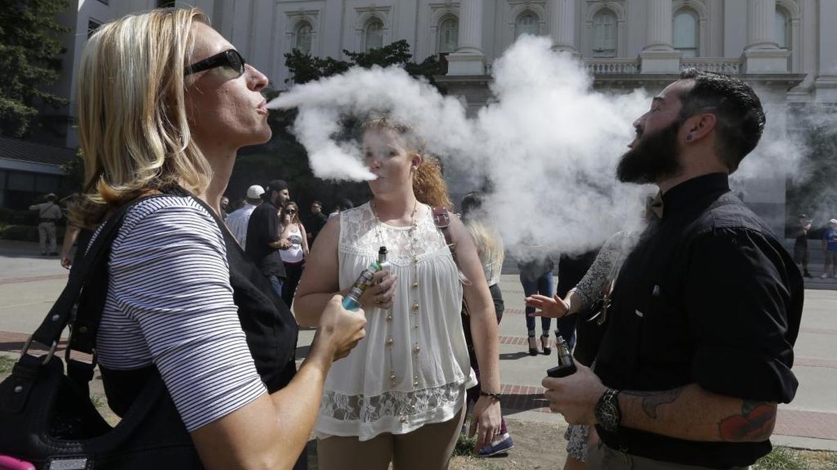 Kari Hess, left, co-owner of Nor Cal Vape, in Redding, Calif., celebrates with Jackie Voisione, center, and Michael Ventura, right, an e-liquid manufacturer from San Diego, after a bill to regulate e-cigarettes stalled in an Assembly Committee, at the Capitol Wednesday, July 8, 2015, in Sacramento, Calif.(AP Photo/Rich Pedroncelli)
