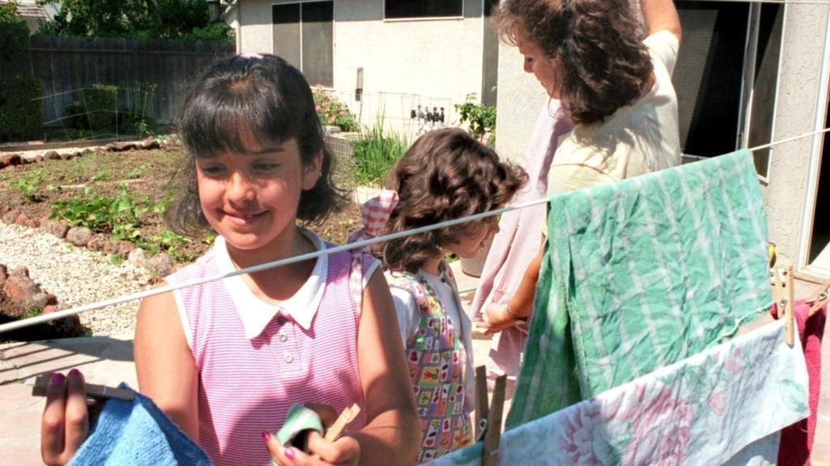 
Jasmine, 10, and Sarah, 8, help their mom Jennifer Khal take down the wash from the clothesline in the backyard on June 12, 1997.
