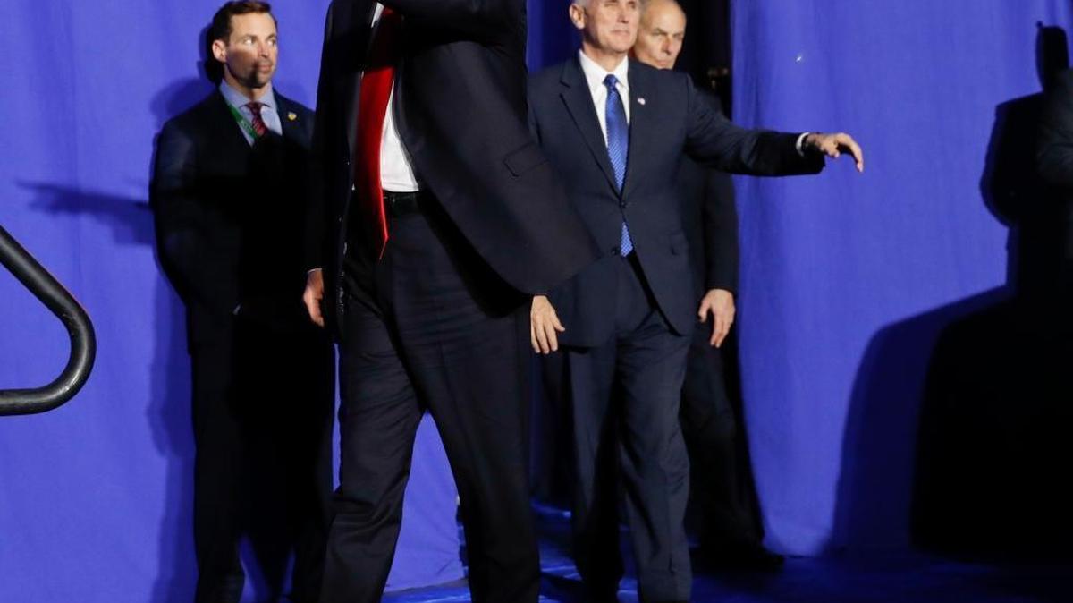 President Donald Trump, accompanied by Vice President Mike Pence, center, and Homeland Security Secretary John F. Kelly, right, gestures as he is introduced before speaking at the Homeland Security Department in Washington, Wednesday, Jan. 25, 2017.