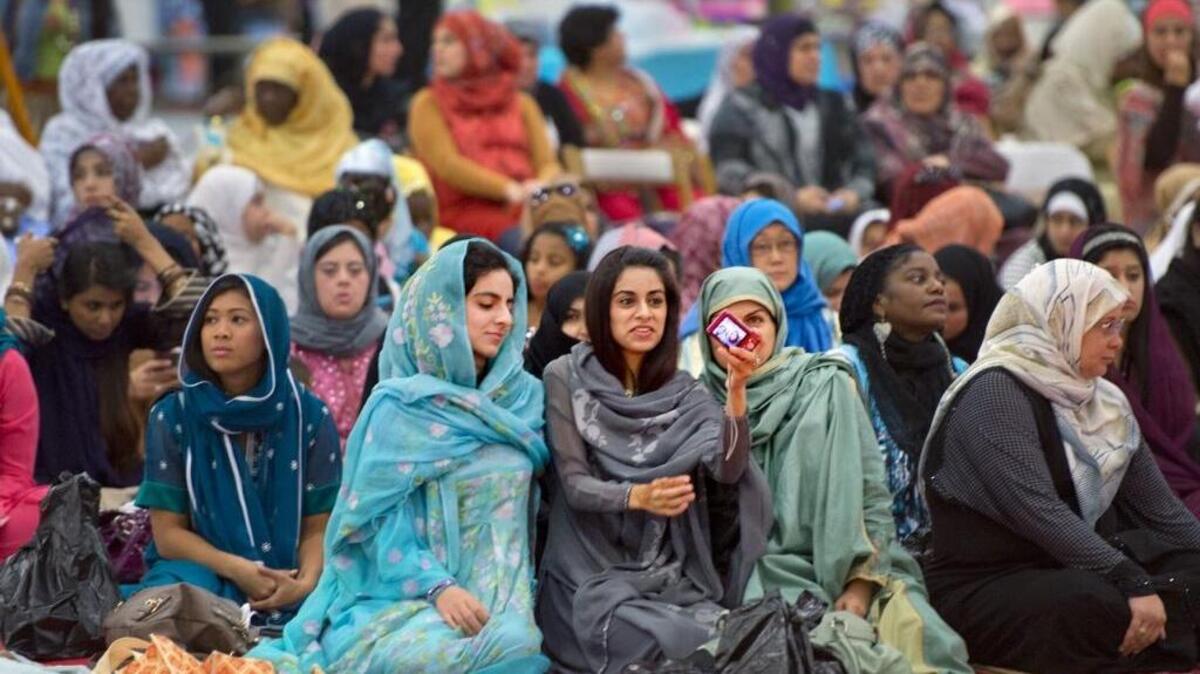 Three young women look at a a picture they took of themselves before the start of the Eid prayer marking the end of Ramadan at McClellan Park on Thursday, August 8, 2013 in Sacramento.