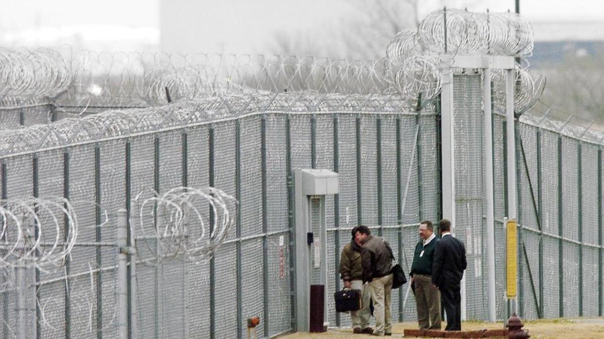 Men wait outside the Cimarron Correctional Facility, in Cushing, Okla., which is owned by the Nashville-based Corrections Corporation of America.