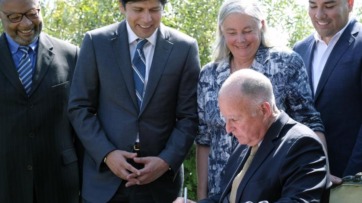 Gov. Jerry Brown, seated, signs climate legislation while joined by Assemblyman Reggie Jones-Sawyer, D-Los Angeles, Senate President Pro Tem Kevin de León, Sen. Fran Pavley, D-Agoura Hills, and Sen. Ricardo Lara, D-Bell Gardens, in Los Angeles on Sept. 8, 2016.