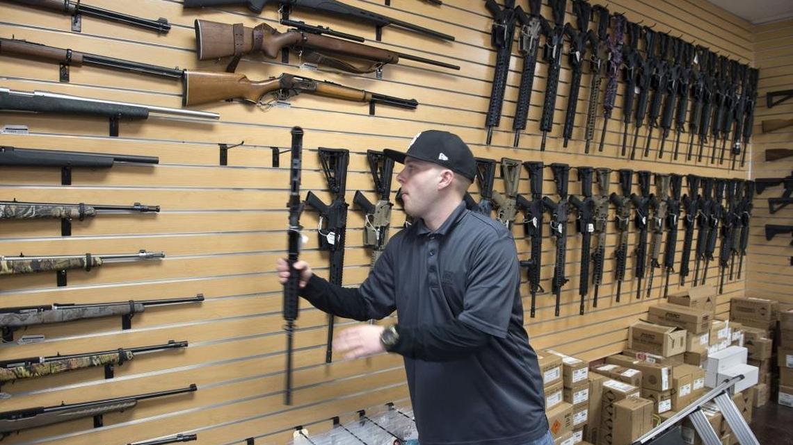 Nate Woodward, manager at Sacramento Black Rifle, a Rocklin gun shop, puts a rifle back on the display wall on Aug. 15, 2016.