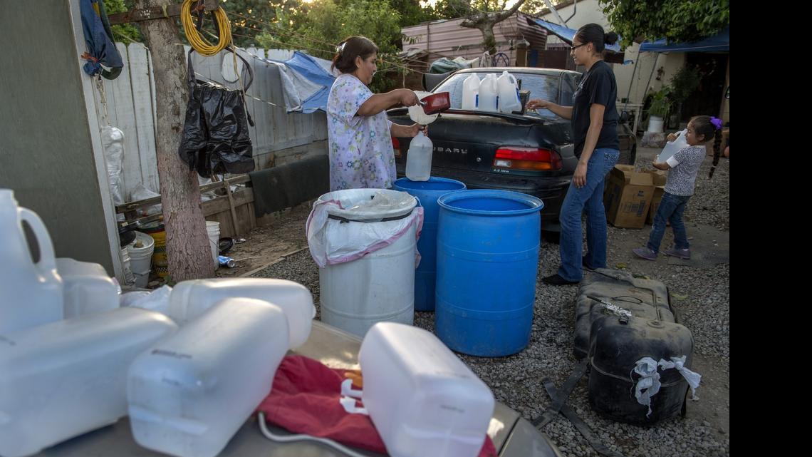 
Maria Jimenez, 54, left, lives in a constant state of transporting water in the Tulare Lake basin. She is helped by her daughter Mireya Romo, 25, and granddaughter Nevaeh Hernandez, 4, as she pours water from large containers her husband brought from working in the grape fields into smaller jugs to be used for essentials inside their home in Monson.
