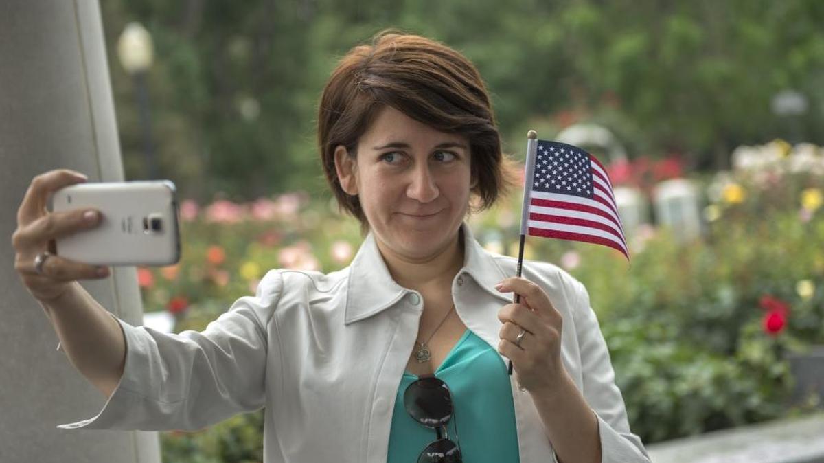 Soraya Manzor, of Chile, takes a selfie underneath the pavilion after the swearing in ceremony to become a U.S. citizen. A bill passed by the Assembly Monday would allow voters to take selfies with their ballots.