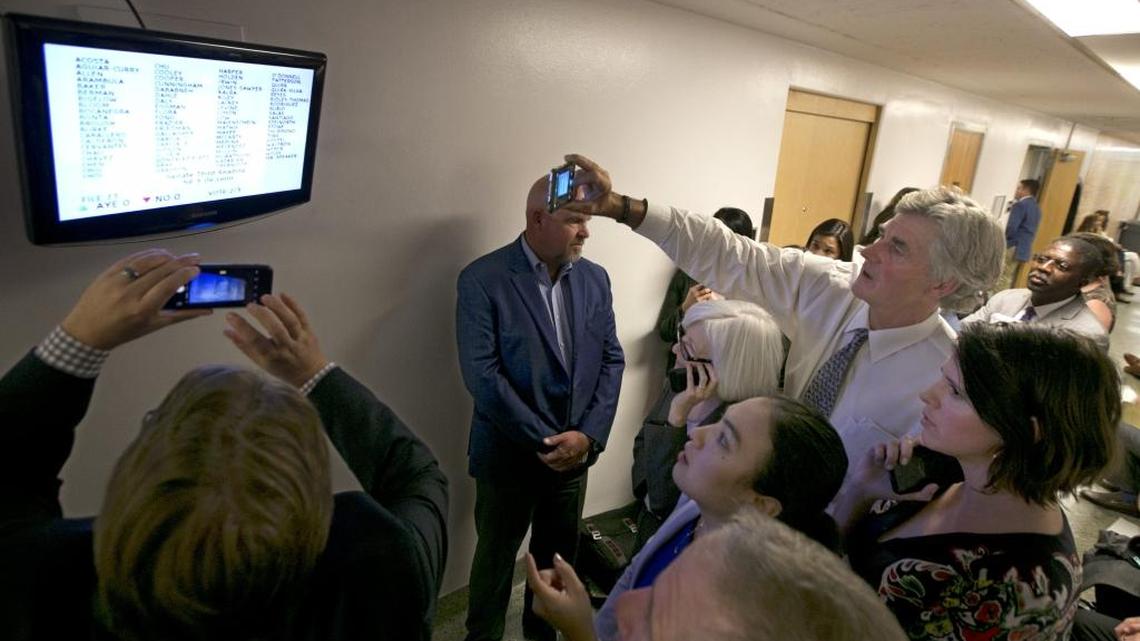 Lobbyists huddle around a television monitor in the hallway of the Capitol displaying the votes on a bill before the state Assembly during the final day of this year’s legislative session Sept. 15 in Sacramento.