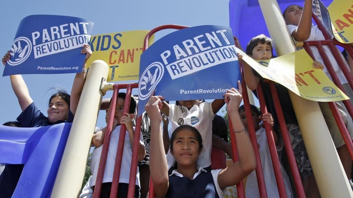 Children hold up "Parent Revolution" signs during a press conference at Mgrdichian Park, next to Desert Trails Preparatory Academy in Adelanto, California on July 30, 2013. They are celebrating the opening of The Desert Trails Preparatory Academy, chartered by Desert Trails' parents to transform the chronically failing elementary school.