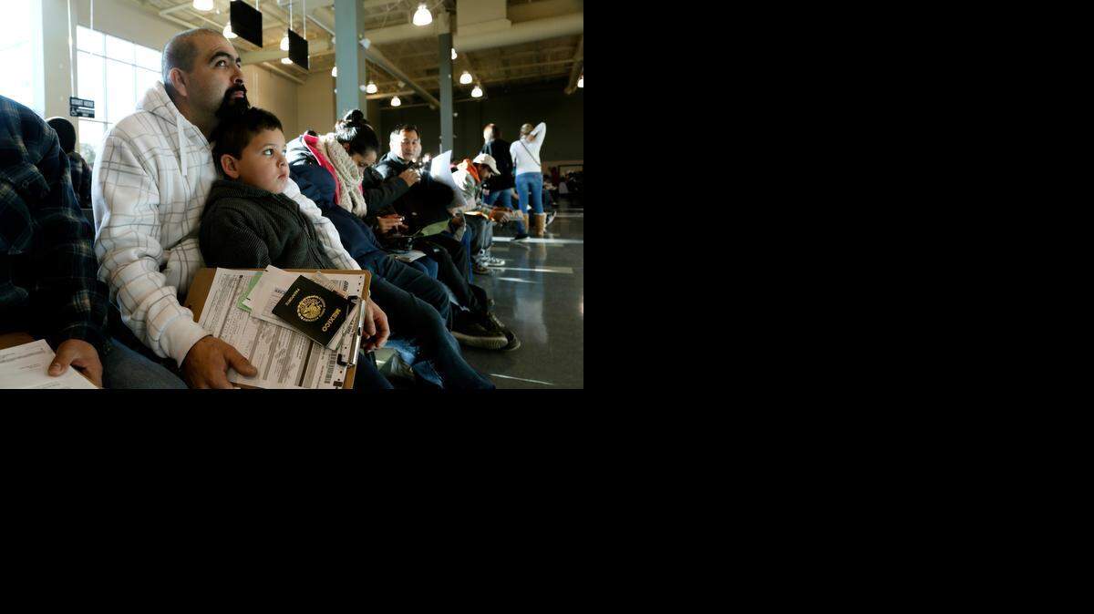 
Miguel Ayala waits with his son Jesus to register for a driver’s license at a Department of Motor Vehicles office in Stanton on Friday. 
