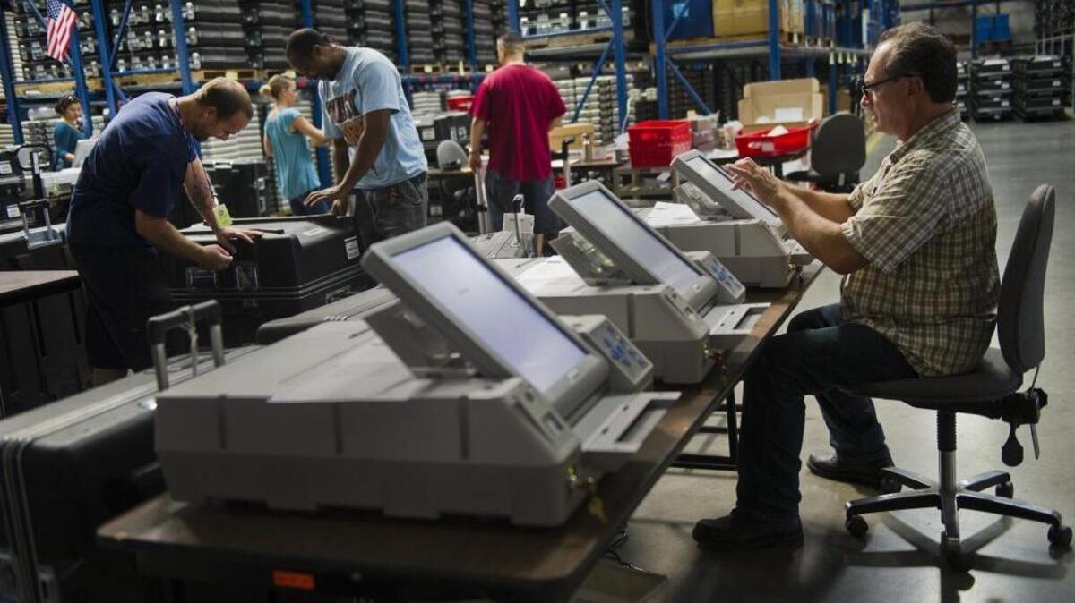 Election clerk Michael Coin, right, calibrates and checks voting machines as they prepare for the November 2012 election. Monday is the last day to register to vote for the June 7, 2016 presidential primary.