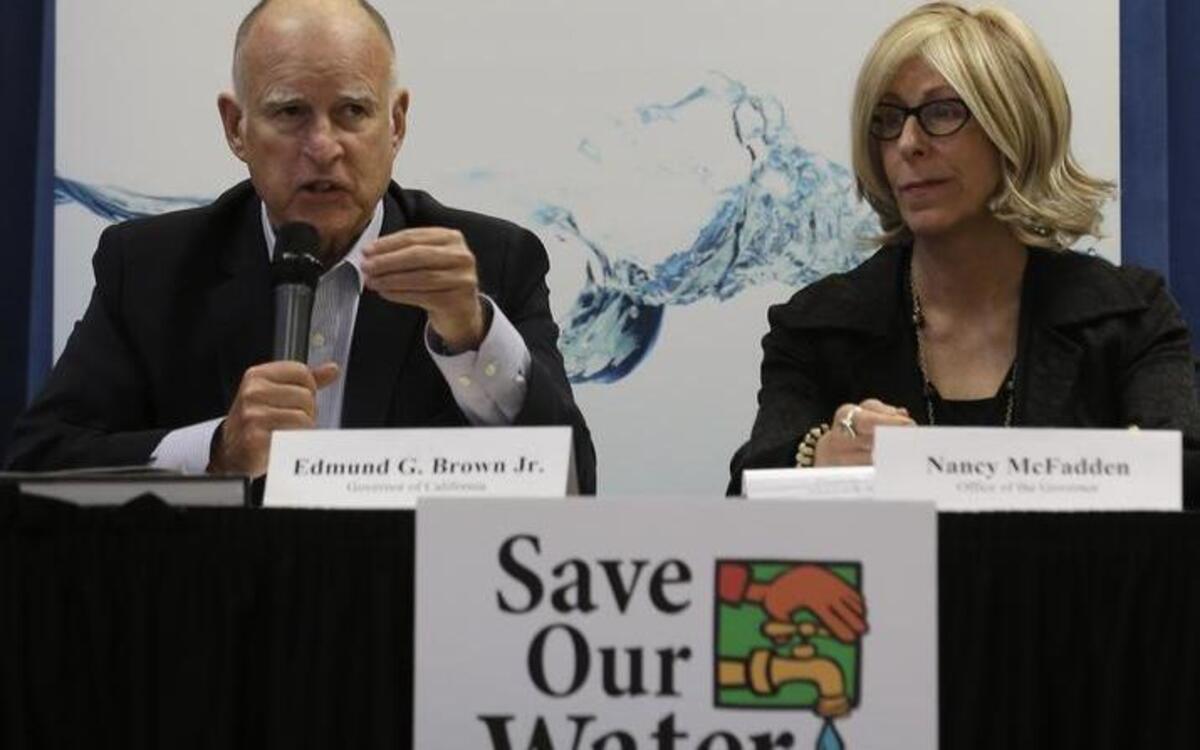 Gov. Jerry Brown talks to reporters at the end of a meeting on the drought, with agricultural, environmental and urban water agency leaders from across California at his Capitol office on April 8, 2015. At right is Brown's Executive Secretary Nancy McFadden.