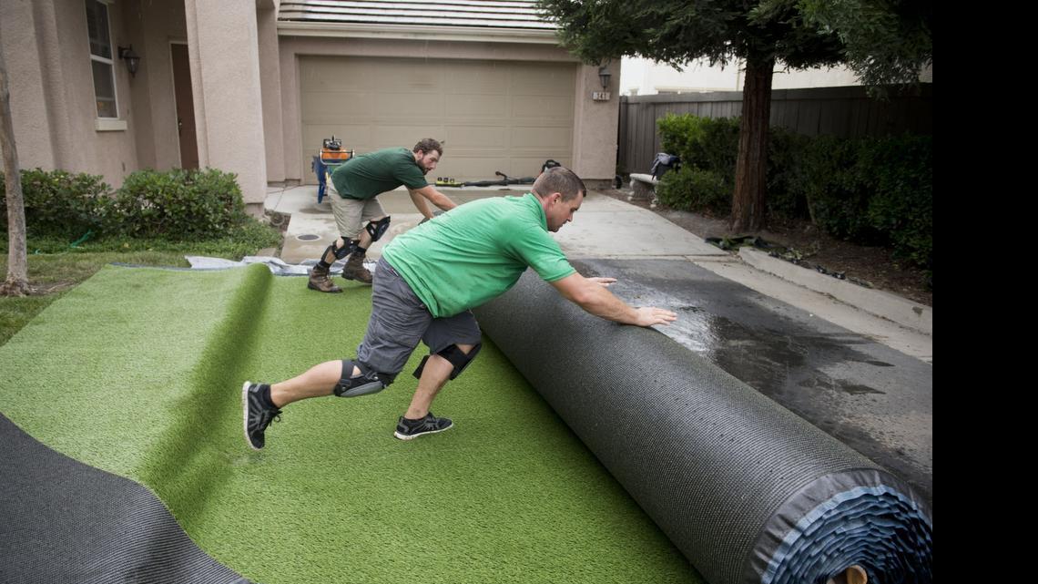 
Brian Lopes, front, and Derick Caron, installers with Pacific Grass and Turf, roll out sections of artificial grass to be cut and placed, Monday, June 8, 2015, at a client's home in North Natomas. 
