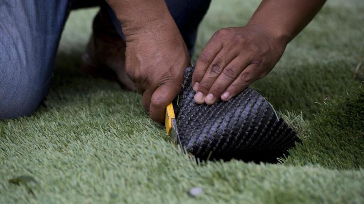 
Antonio Guerra, an installer with Pacific Grass and Turf, cuts artificial grass, Monday, June 8, 2015, at a client's home in North Natomas.
