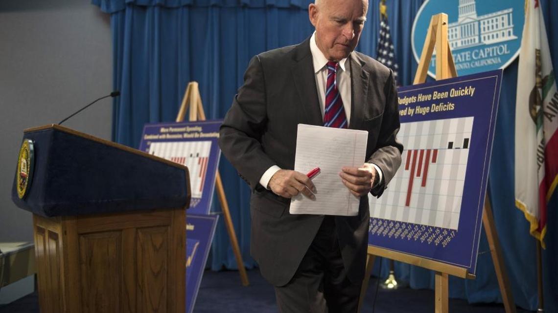 Gov. Jerry Brown carries notebook paper outlining his proposed 2016-17 state budget after a news conference at the California State Capitol Thursday, Jan. 7, 2016, in Sacramento, Calif.