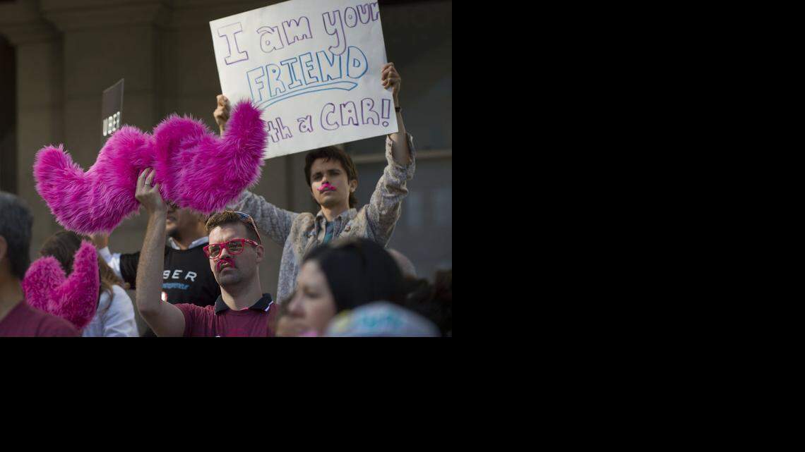 
Ridesharing supporters hold signs during a rally at the state Capitol in Sacramento on Tuesday, June 17, 2014. The pink furry mustache is the symbol for Lyft.
