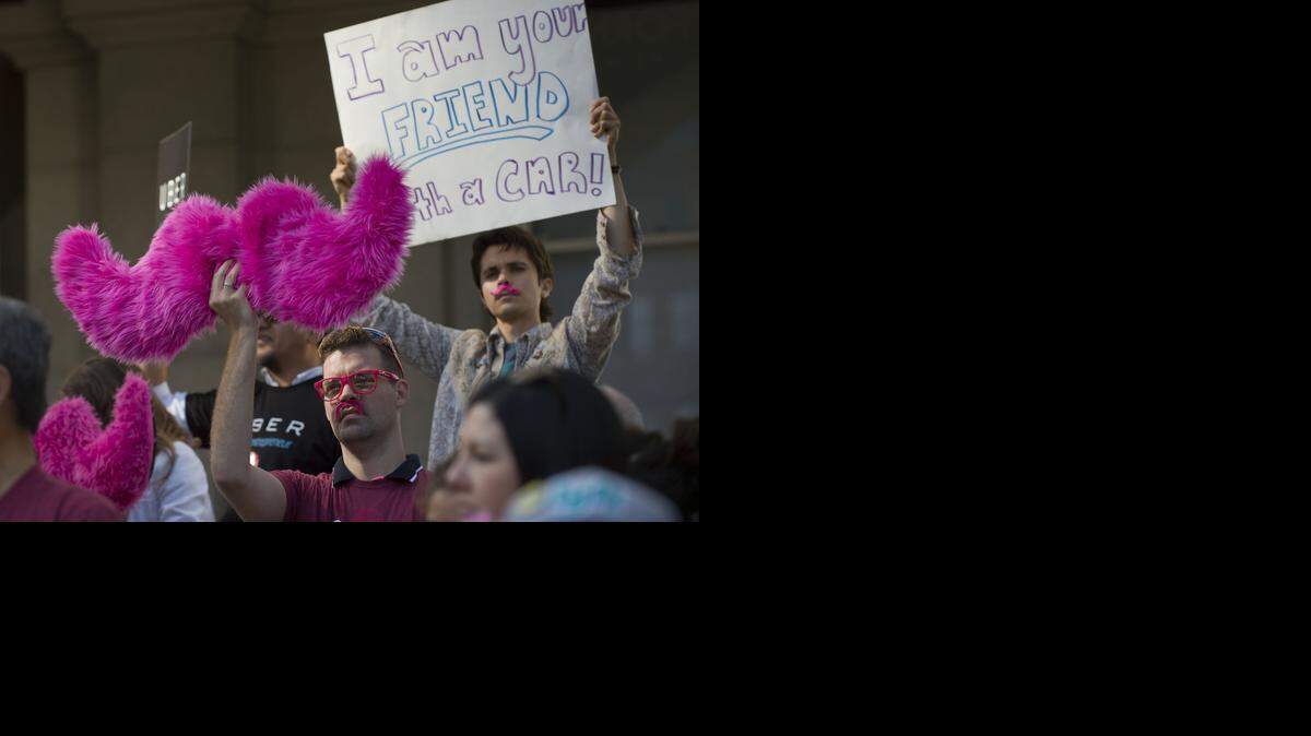 
Ridesharing supporters hold signs during a rally at the state Capitol in Sacramento on Tuesday, June 17, 2014. The pink furry mustache is the symbol for Lyft.
