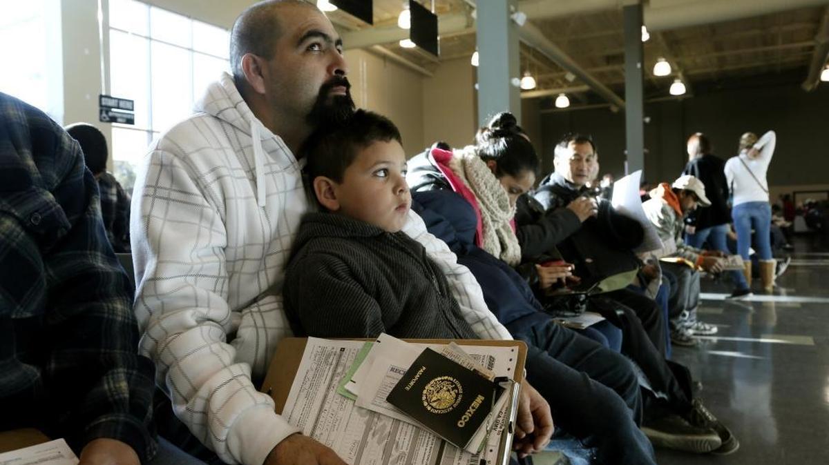 Miguel Ayala waits with his son, Jesus, and other immigrants to register for a driver’s license at a California Department of Motor Vehicles office in Stanton, Calif., on Jan. 2, 2015.