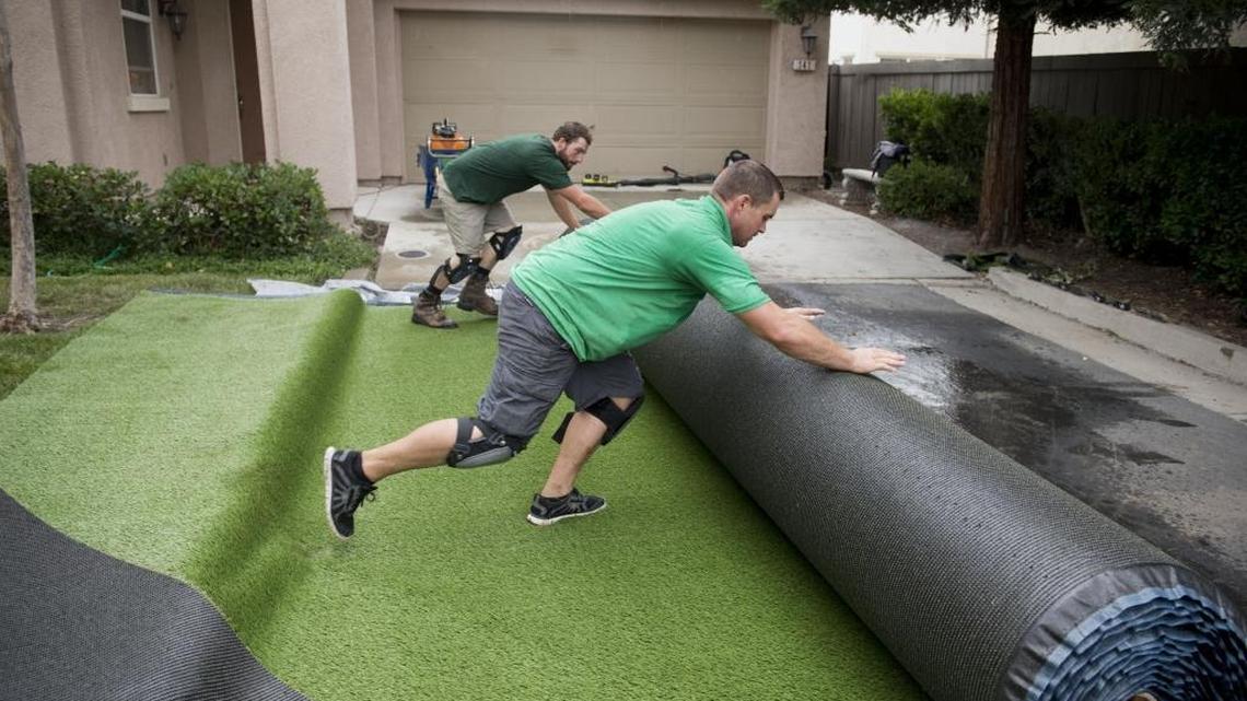 
Brian Lopes, front, and Derick Caron, installers with Pacific Grass and Turf, roll out sections of artificial grass to be cut and placed on Monday, June 8, 2015, at a client’s home in North Natomas.
