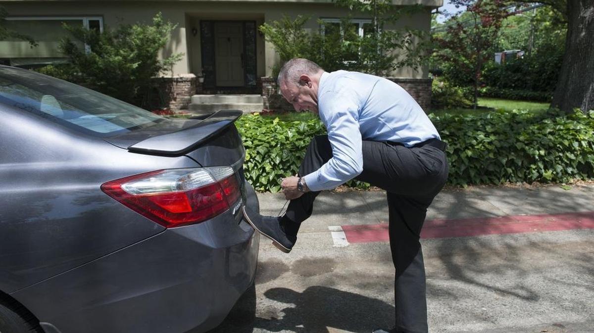 Darrell Steinberg ties his walking shoes on the bumper of his car before he walks door to door for a couple of hours in Land Park as he campaigns for mayor on Thursday, May 12, 2016, in Sacramento, Calif.