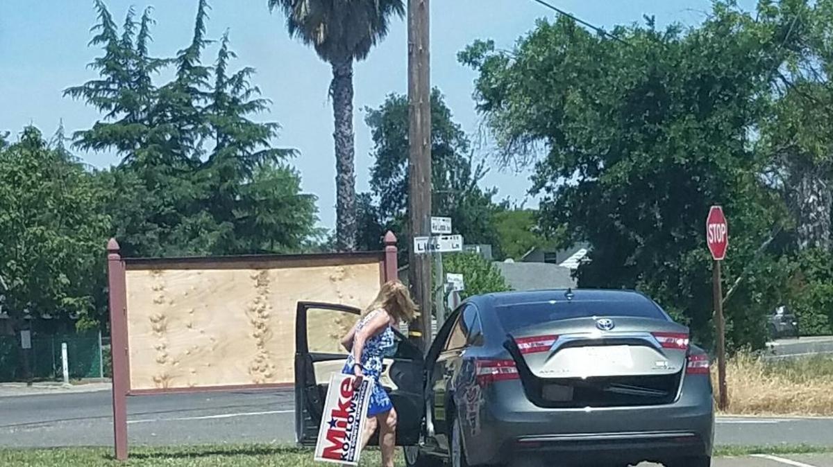 In this photo taken by a resident, Sacramento County supervisor candidate Teresa Stanley is seen holding a sign for rival Mike Kozlowski as she stands outside her car. Stanley says Kozlowski didn’t have permission to place the sign where it was. Pastor Steve Gleghorn, whose church sits on adjacent property, said that Kozlowski didn’t have his permission, but that the church doesn’t own the property and that the church is fine with any candidate placing signs there.