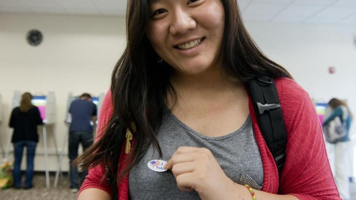 University of California, Davis student Lorraine Ye puts on her "I Voted" sticker after casting her vote on campus in Davis, Calif. on Tuesday, November 6, 2012.