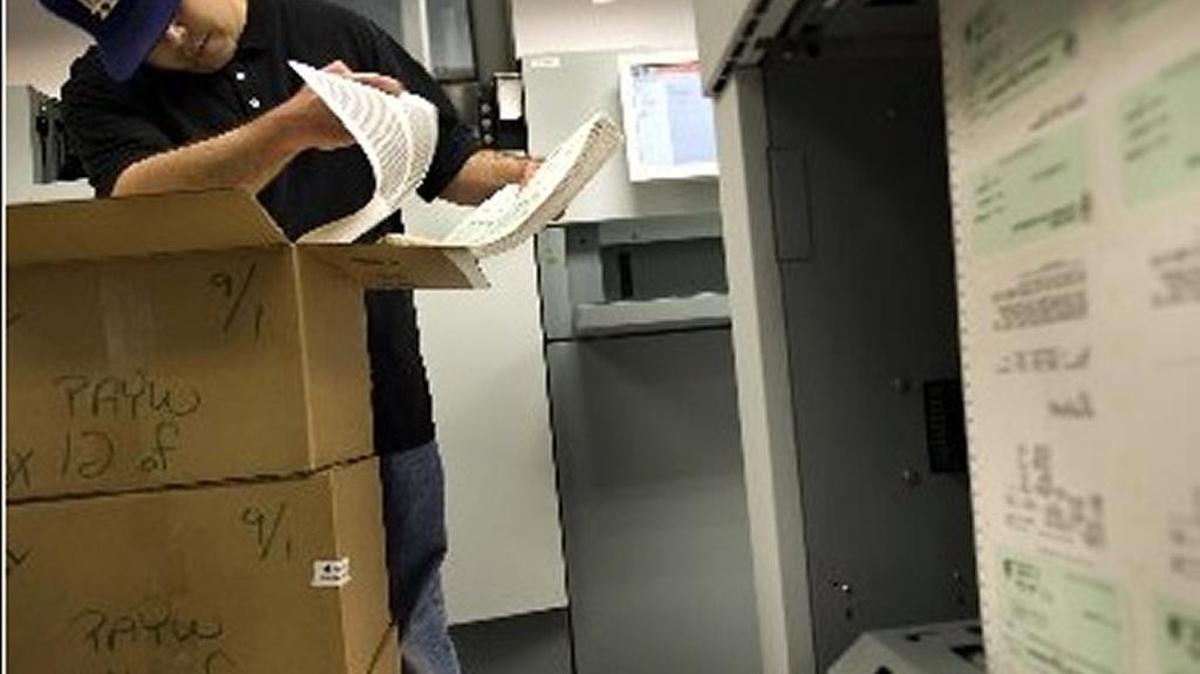 An employee at the the State Controller’s Office reviews paychecks as they come off the printer.