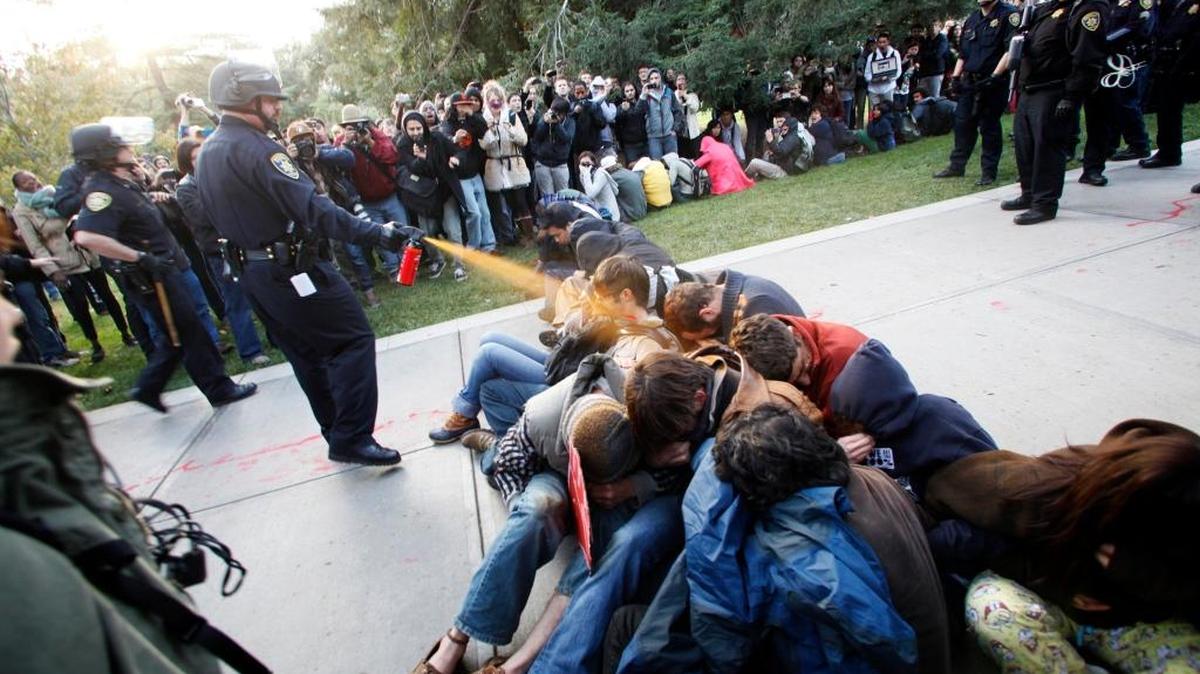 In this Nov. 18, 2011 file photo, University of California, Davis Police Lt. John Pike uses pepper spray to move Occupy UC Davis protesters while blocking their exit from the school's quad in Davis, Calif.