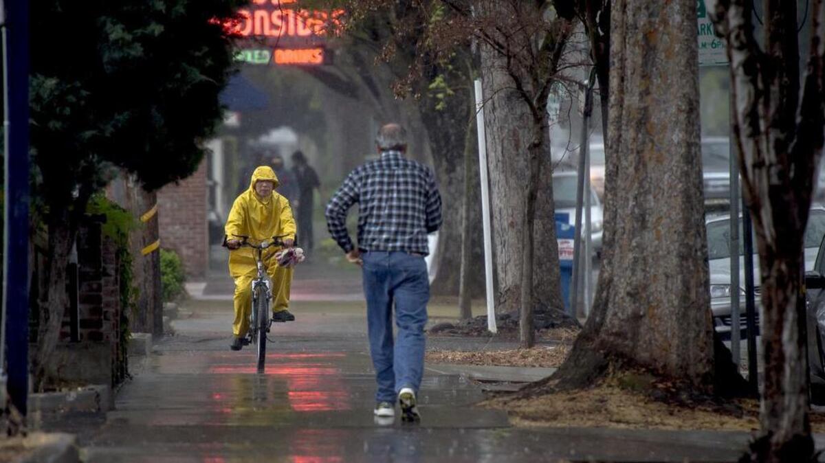 Along 10th Street a bicyclist was prepared but the pedestrian not so much as rain and thunder hit the Sacramento area in 2016.