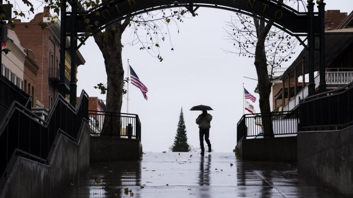 A pedestrian in Old Sacramento stays dry with an umbrella during a rainstorm last January. The National Weather Service predicts a chance of rain next week, following a lengthy dry spell.