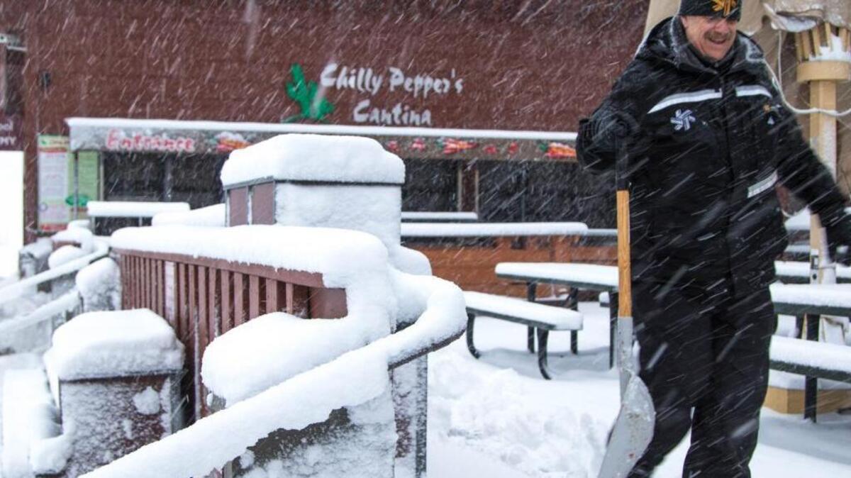 In this photo provided by Northstar California Resort, a worker walks past heavy snowfall on the deck of the Lodge at Big Springs Monday, Dec. 21, 2015, in Truckee, Calif.
