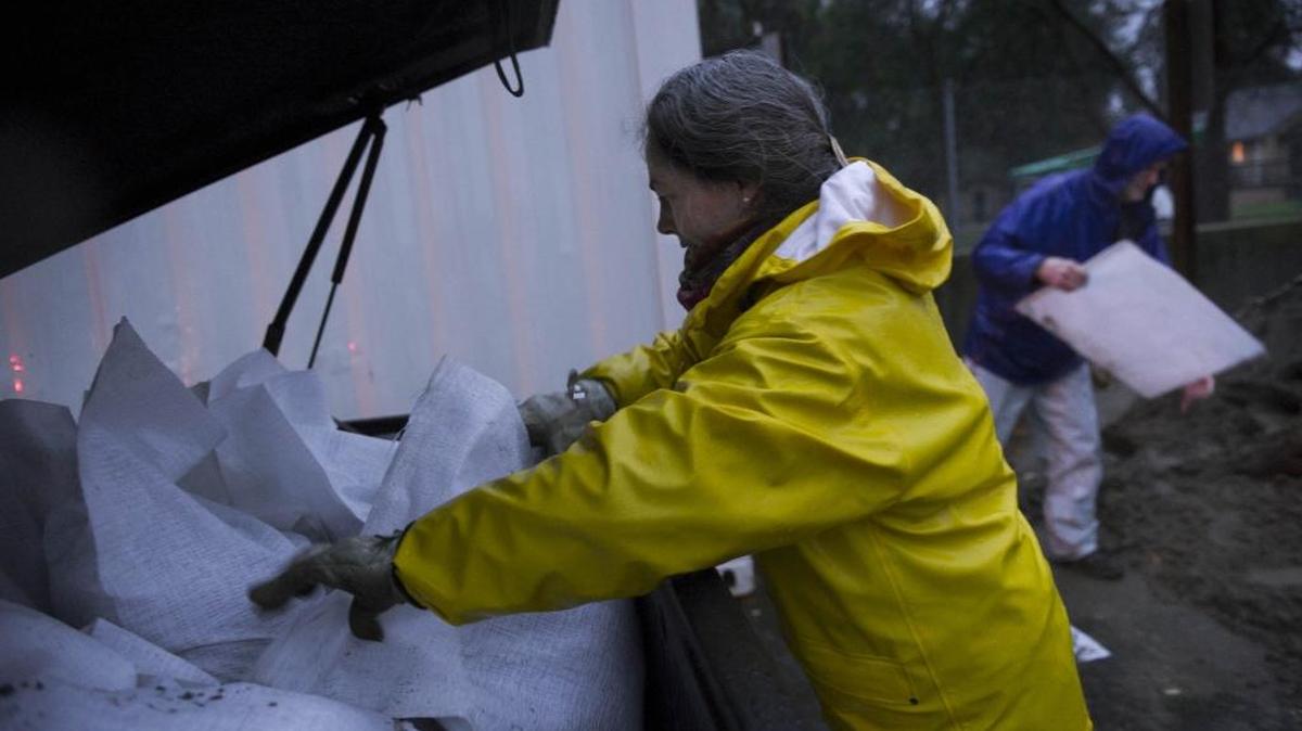 Becca and Randy Smith prepare sandbags to protect their neighbor’s home from the overflowing Arcade Creek in 2014 in Sacramento.