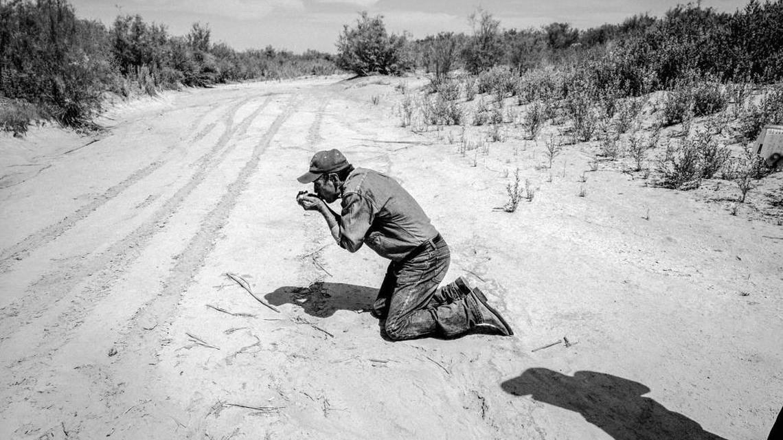 Local environmentalist Juan Butrun pretends to drink water from the dry channel of the Colorado River downstream from the Morelos Dam.
