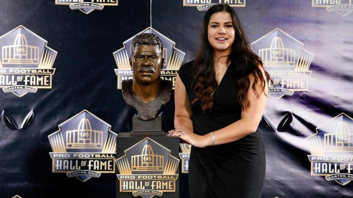 
Sydney Seau, the daughter of former NFL player Junior Seau, poses with a bust of her father during an induction ceremony at the Pro Football Hall of Fame on Aug. 8 in Canton, Ohio. 
