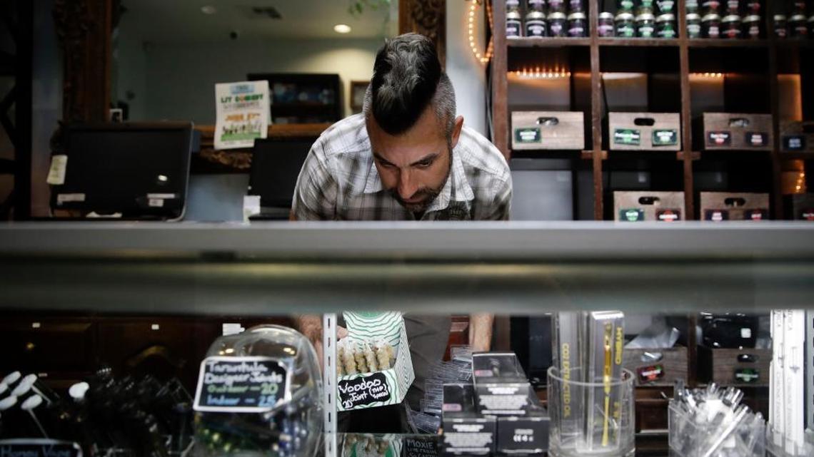In this June 27, 2017, photo, Jerred Kiloh, owner of the Higher Path medical marijuana dispensary, stocks shelves with with cannabis products near Los Angeles in Sherman Oaks. On a typical day, he has told state authorities, $15,000 can change hands in his dispensary. The cash must not only be counted repeatedly to safeguard against loss,but state and local taxes also must be set aside and stored, sometimes for a month or more. (AP Photo/Jae C. Hong)